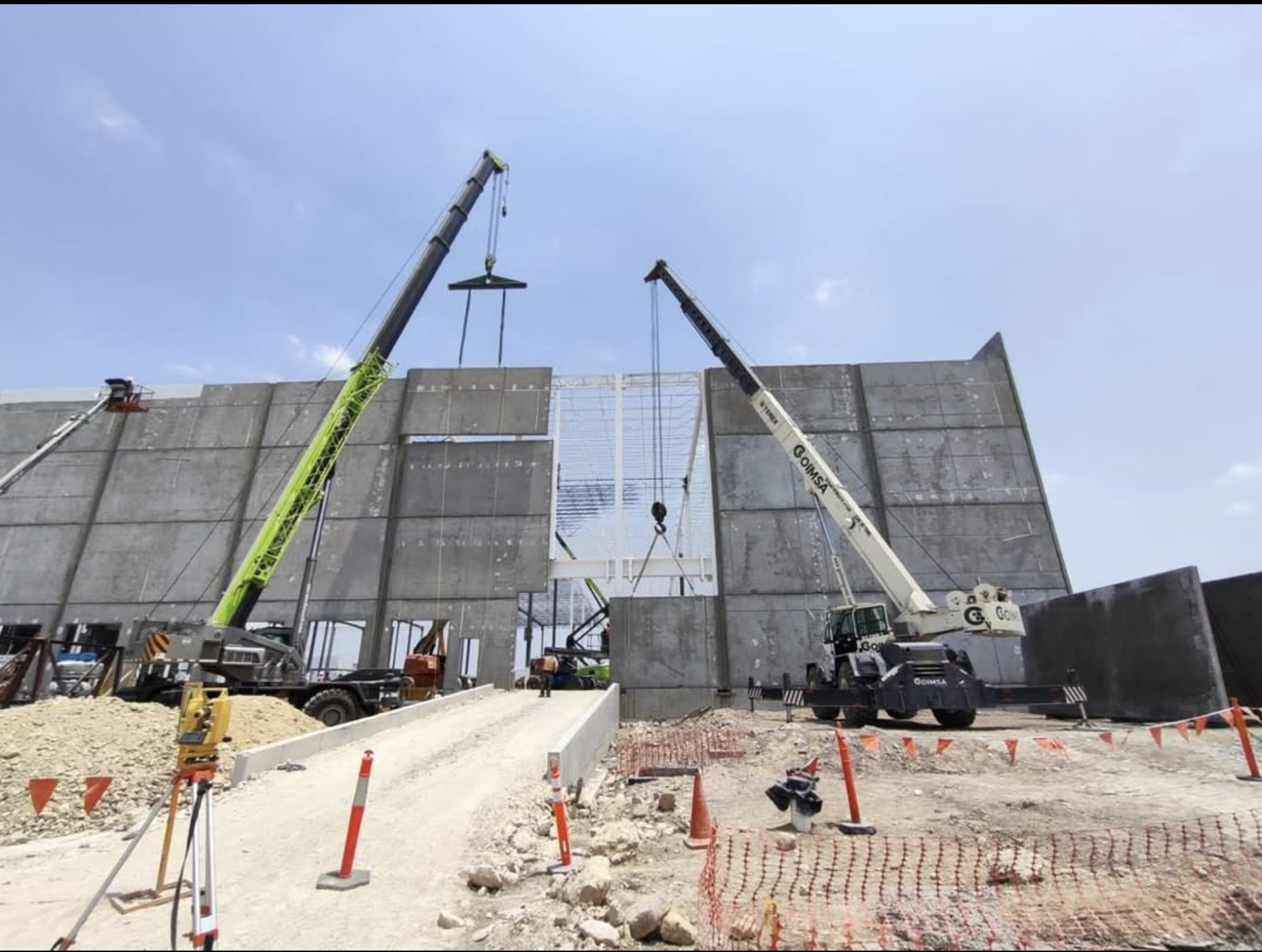 Dos grúas montando panel de concreto entre muros Tilt-Up